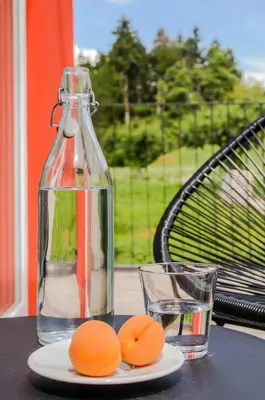 a bottle of water and two oranges on a table with a glass at B&B Lupo in Cavareno