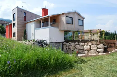 a house on a hill with a stone wall at B&B Lupo in Cavareno