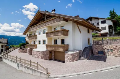 a large white house with a wooden roof at Appartamenti Casa Salesai in Carano