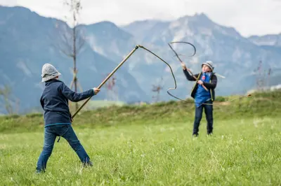 two people playing with a bow and arrow in a field at Plonerhof - Ferienhaus Maria in Rodengo