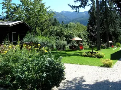 a garden with flowers and trees and a house at Azalea Park Hotel in Cavalese