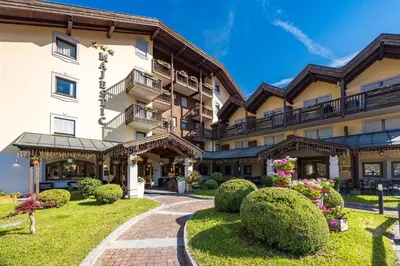 an exterior view of a hotel with a garden at Aparthotel Majestic in Predazzo