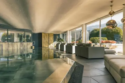 a living room with couches and tables and windows at Golserhof in Tirolo