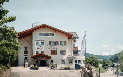 a building with a flag in front of it at Hotel Ludwigshof & Luvina in Trodena
