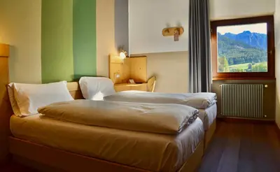 a hotel room with two beds and a window at Hotel Garni Edy in Daiano