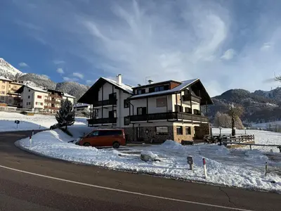 a house with a car parked in front of it in the snow at Hotel Garni Edy in Daiano