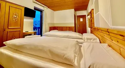 three beds in a room with a window at Hotel Garni Edy in Daiano