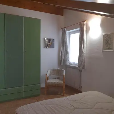 a bedroom with a green cabinet and a chair at Col Rodella in Campitello di Fassa