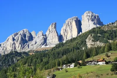 a mountain range with houses in a green field at Col Rodella in Campitello di Fassa