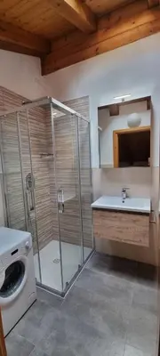 a bathroom with a shower and a sink and a washing machine at Col Rodella in Campitello di Fassa