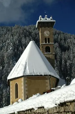 a building with a clock tower with snow on it at Col Rodella in Campitello di Fassa