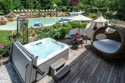 a pool with a hot tub and a swing at Villa Orso Grigio in Ronzone