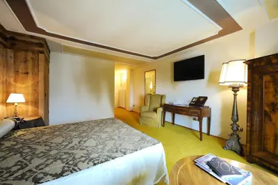a bedroom with a bed and a desk and a television at Villa Orso Grigio in Ronzone