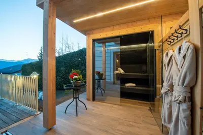 a wooden deck with a glass door leading to a bedroom at Villa Orso Grigio in Ronzone