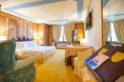 a hotel room with a bed and a table and chairs at Villa Orso Grigio in Ronzone