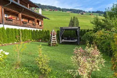 a garden with a chair and a ladder in front of a house at Roderhof in Braies