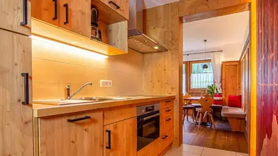 a kitchen with wooden cabinets and a sink and a table at Roderhof in Braies
