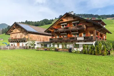 a large wooden house in a green field at Roderhof in Braies