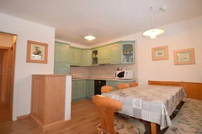 a kitchen with green cabinets and a table with chairs at Aliza in Campitello di Fassa