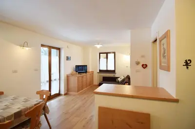 a living room with a table and a kitchen at Aliza in Campitello di Fassa