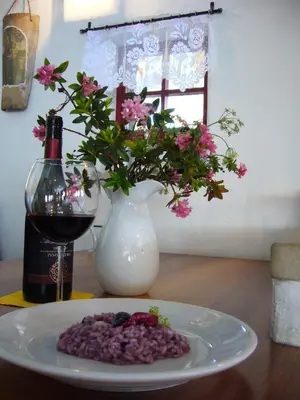 a plate of food and a bottle of wine and a vase with flowers at Rifugio Monti Pallidi in Canazei