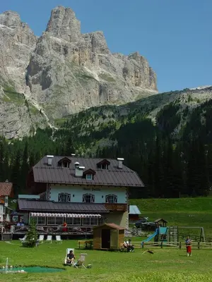 a building in a field with a mountain in the background at Rifugio Monti Pallidi in Canazei