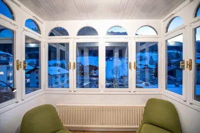 a room with two chairs and windows with a view at Apartments Stina in Ortisei