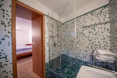 a bathroom with a glass shower with a sink at Apartments Stina in Ortisei