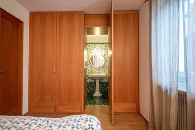 a bedroom with a door to a bathroom with a sink at Apartments Stina in Ortisei
