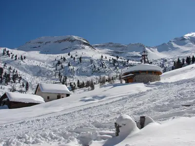 a snow covered mountain with a building in the distance at Piccolo Hotel Claudia No Pets in San Vigilio Di Marebbe