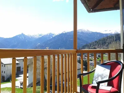 a chair on a balcony with a view of mountains at Hotel Serenella in Canale San Bovo