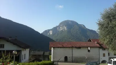 a mountain in the background of a village with buildings at Hotel Serenella in Canale San Bovo