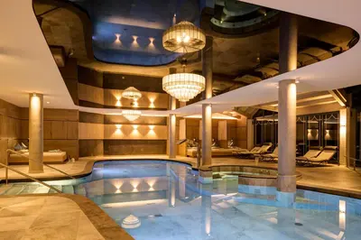 a pool in a hotel lobby with chandeliers at Hotel Burggräflerhof in Merano