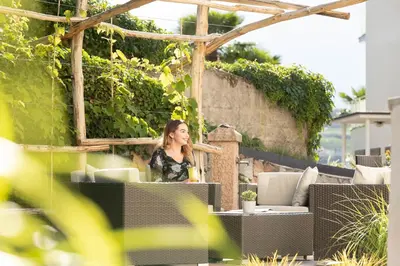 a woman standing on a patio in a garden at Hotel Burggräflerhof in Merano
