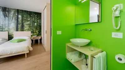 a green bathroom with a sink and a bedroom at Hotel B&B Andreas in Canazei