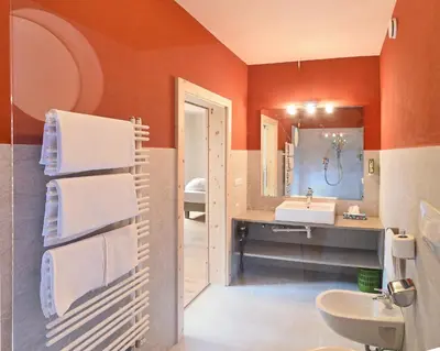 an orange bathroom with a sink and a mirror at Hotel Gassenwirt in Chienes
