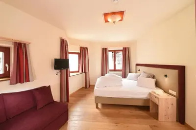 a bedroom with a bed and a couch at Hotel Gassenwirt in Chienes