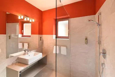an orange bathroom with a sink and a shower at Hotel Gassenwirt in Chienes