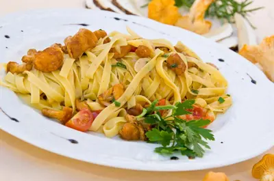 a white plate of pasta with meatballs and vegetables at Hotel Gassenwirt in Chienes