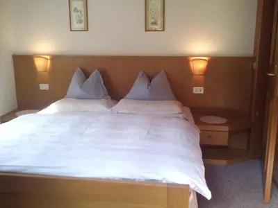 a bedroom with a large bed with white sheets and pillows at Residence Soratru in San Vigilio Di Marebbe