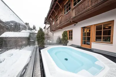 a hot tub on the patio of a house in the snow at Hotel Dolomiti in La Villa