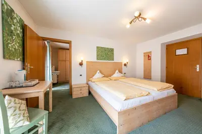 a bedroom with a large bed and a desk at Hotel Dolomiti in La Villa