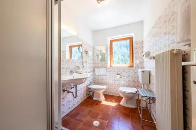 a bathroom with a toilet and a sink and a mirror at Hotel Dolomiti in La Villa