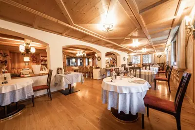 a restaurant with two tables with white tablecloths at Hotel Dolomiti in La Villa