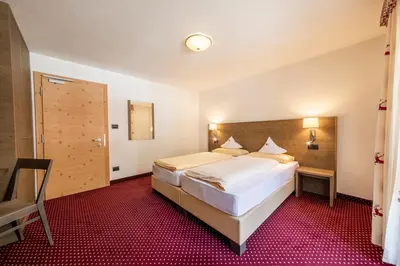 a bedroom with a large bed and a red carpet at Hotel Dolomiti in La Villa