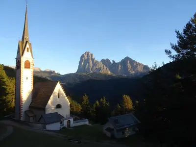an old church with a mountain in the background at Albergo Somont in Ortisei