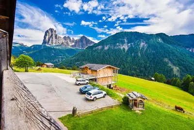 two cars parked in a parking lot in front of a mountain at Albergo Somont in Ortisei