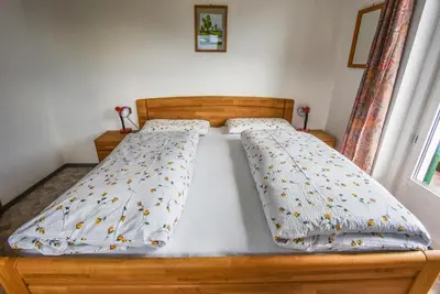 a bed with a wooden bed frame with a comforter at Albergo Somont in Ortisei