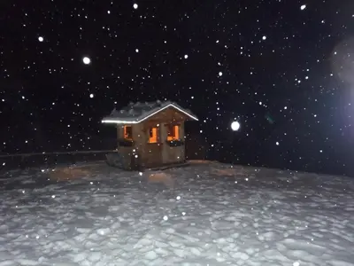 a small house in the snow at night at Albergo Somont in Ortisei
