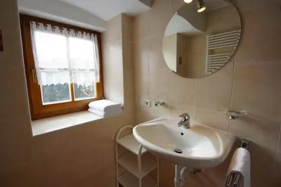 a bathroom with a sink and a mirror and a window at Soroea in San Vigilio Di Marebbe